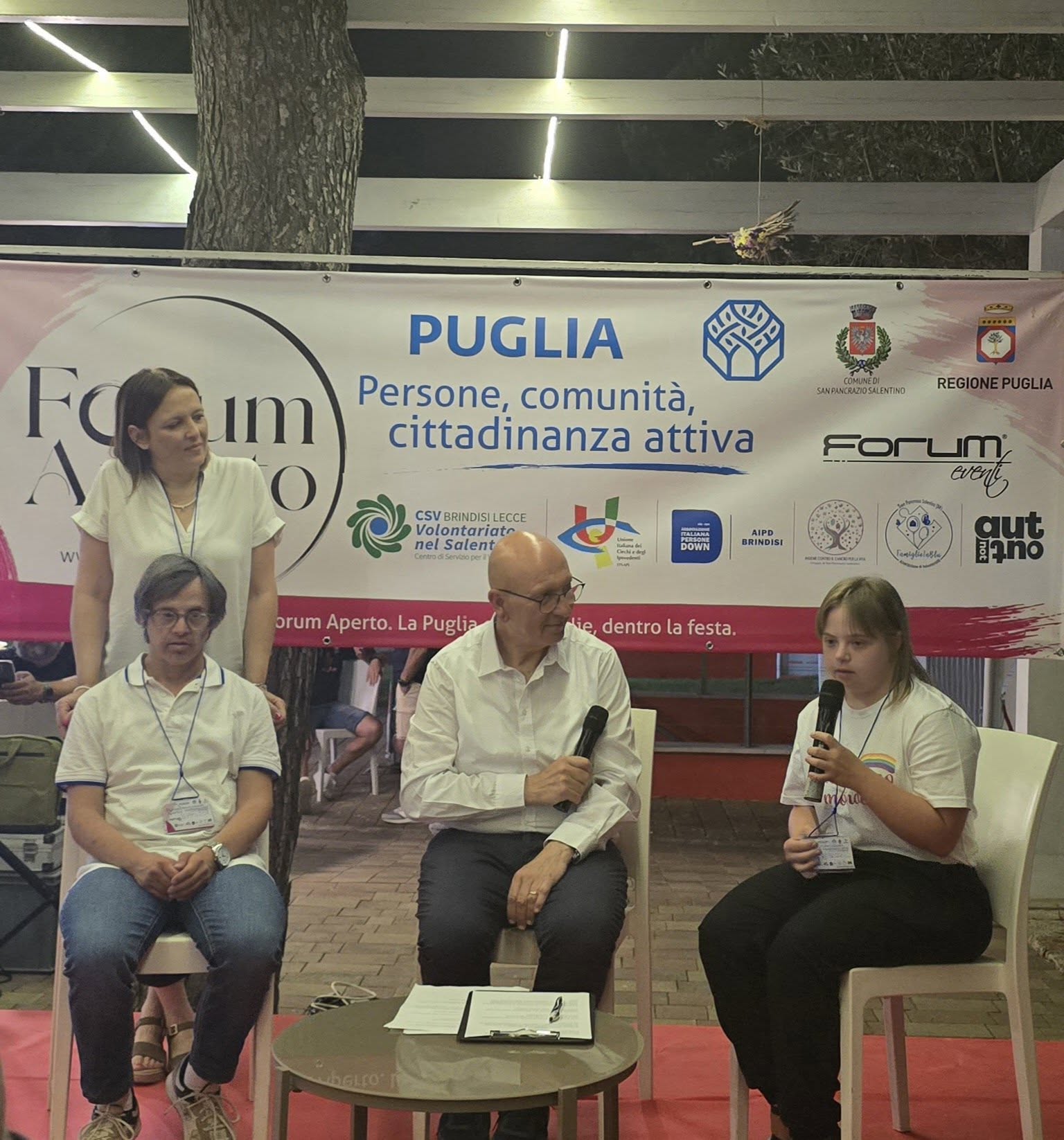 I ragazzi di AIPD Brindisi sul palco del talk, al microfono davanti al banner di Forum Aperto