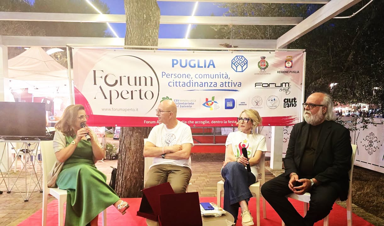 Il tavolo dei relatori della serata conclusiva davanti al banner di Forum Aperto