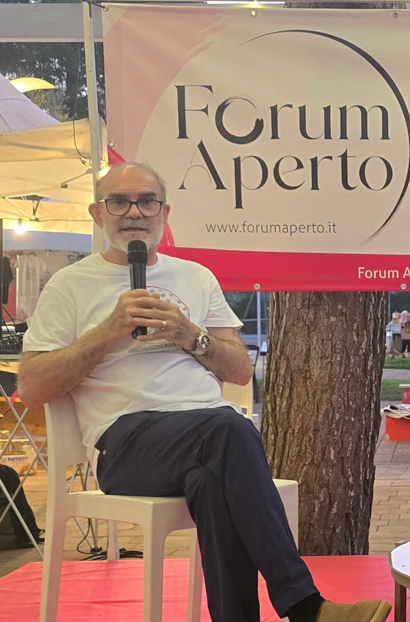 Antonio Ripa del gruppo Insieme contro il cancro per la vita al microfono davanti al banner di Forum Aperto